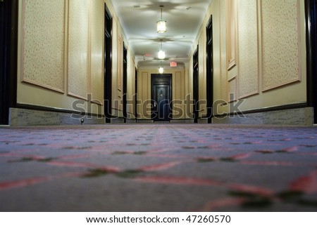 Low angle view of a hotel hallway with a doors on the side and at the end.