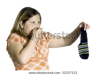 A young girl plugging her nose because of the smell of a stinky sock, isolated against a white background.