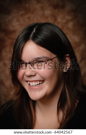 A young preteen girl laughing when she\'s getting her portrait done