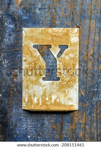 Metal typography over a weathered wood background showing the alphabet letter 