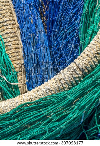 Close-up of fishing nets stacked in the harbor, paying particular attention to the colors, textures, materials, details, knots, etc.