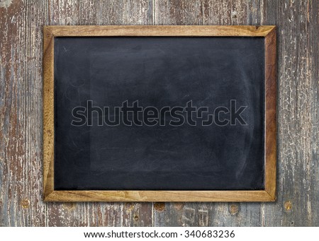 Front view of a blank blackboard over a weathered wooden surface