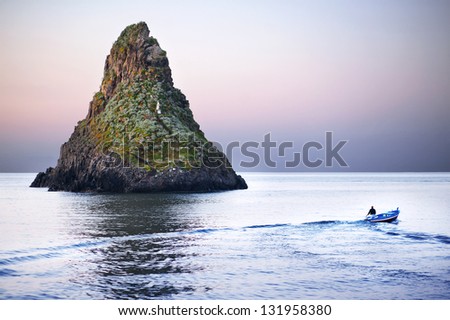 Island in the Sea - beautiful volcanic island in the Mediterranean sea with a fisherman going out to fish for the day