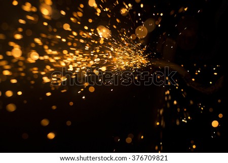 Glowing flow of steel metal spark dust particles and bokeh shine in the dark background