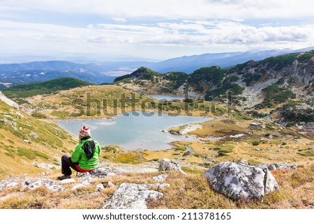 Woman tourist sitting on rock and looking towards mountain lakes in Bulgaria. Rila national park, Seven Lakes.