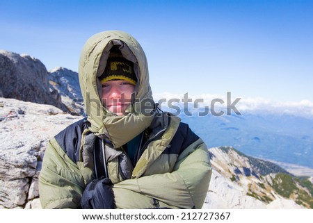 Young woman muffled in down coat standing on mountain in Pirin national park, Bulgaria.