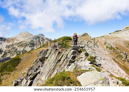 Female mountaineer standing on mountain ridge and drinking water. Pirin national park, Bulgaria.