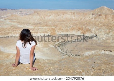 Young woman girl sitting resting on desert mountain cliff edge. Negev mountains, Israel.