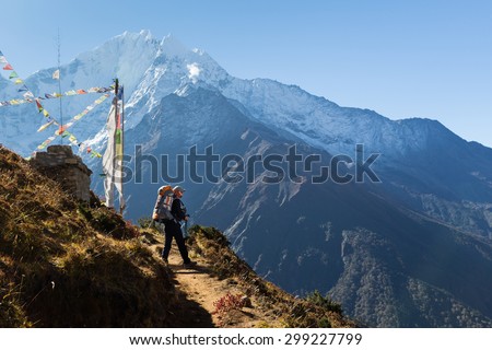 Young woman backpacker standing buddhist stupa in front Kangtega mountain snow peaks ridge. Everest Base Camp route trail, Nepal trekking, Himalaya tourism.