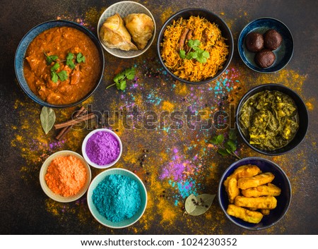 Traditional assorted Indian food, Holi colours powder, rustic background. Indian Holi holiday. Indian dishes and snacks set. Holi celebration. Top view. Festive Indian table setting. Space for text