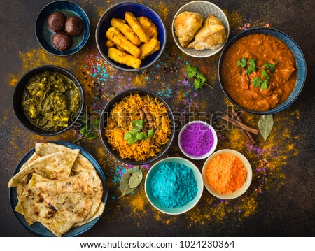 Traditional Indian food, Holi colours powder, rustic background. Indian Holi holiday. Indian dishes and snacks set. Holi celebration. Top view. Festive Indian table setting. Party food selection