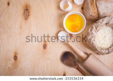 Baking background with bread, eggshell, bread, flour, rolling pin. Vintage wood table from above. Rustic background with free text space.