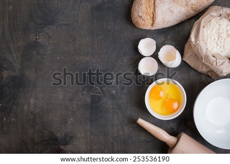 Baking background with blank cook book, eggshell, bread, flour, rolling pin. Vintage wood table from above. Rustic background with free text space.