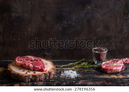 Raw meat steak on dark wooden background ready to roasting