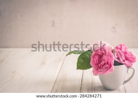 Beautiful pink tea roses on a white wooden background. Romantic background. Vintage shabby frame