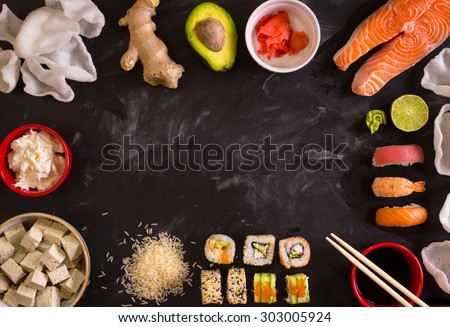 Set of traditional japanese food on a dark background. Sushi rolls, nigiri, raw salmon steak, rice, cream cheese, avocado, lime, pickled ginger. Asian food frame. Dinner party.