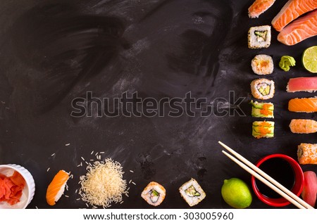 Set of traditional japanese food on a dark background. Sushi rolls, nigiri, raw salmon steak, rice, cream cheese, avocado, lime, pickled ginger. Asian food frame. Dinner party.