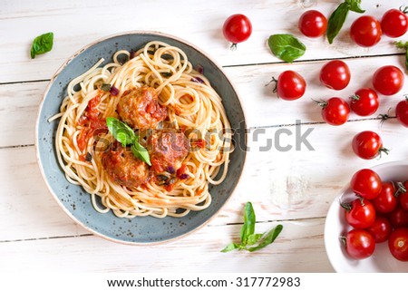 Close-up of delicious spaghetti with meatballs and tomato sauce on a plate. Serving on a white rustic wooden table. An Italian-American dish. Top view. Selective focus