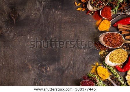 Set of various aromatic colorful spices in old vintage spoons and herbs on a dark wooden background. Space for text. Food frame. Ingredients for cooking. Top view