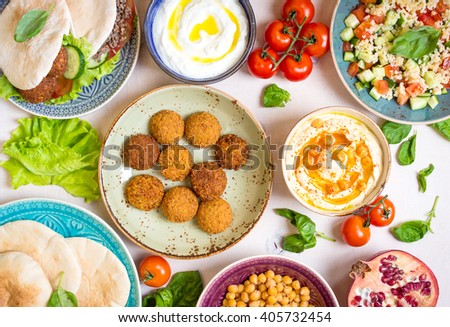 Table served with middle eastern traditional dishes. Bowl with falafel, doner kebap, vegetarian pita, hummus, tabbouleh bulgur salad, chickpea, olive oil dip, pomegranate. Top view. Dinner party