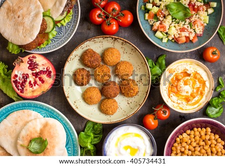 Table served with middle eastern traditional dishes. Bowl with falafel, doner kebap, vegetarian pita, hummus, tabbouleh bulgur salad, chickpea, olive oil dip, pomegranate. Top view. Dinner party