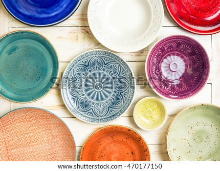 Different antique vintage multicolored empty plates and bowls on a white old wooden table. Table setting. Shabby chic/retro style. Top view. Tableware. Rustic kitchen. Set of plates. Toned image
