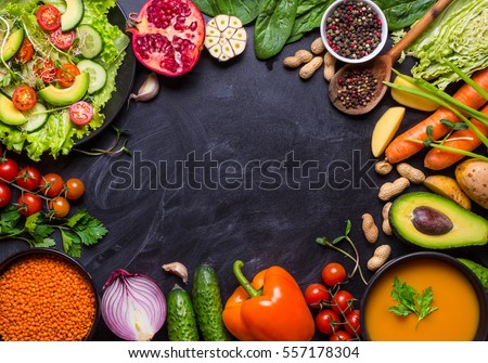 Vegan food and dishes. Pumpkin soup, salad, vegetables, fruits, lentils on rustic black chalk board background. Healthy, clean eating concept. Vegan or gluten free diet. Space for text. Vegan dinner