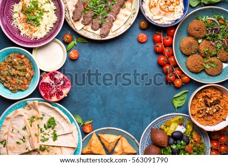 Middle eastern or arabic dishes and assorted meze on concrete rustic background. Meat kebab, falafel, baba ghanoush, hummus, sambusak, rice, tahini, kibbeh, pita. Halal food. Space for text. Top view