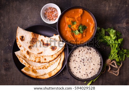 Hot spicy chicken tikka masala in bowl. Chicken curry with rice, indian naan butter bread, spices, herbs. Traditional Indian/British dish, popular indian curry in UK. Top view. Indian food. Close-up