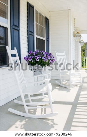 white rocking chairs with purple petunias on a suburban covered porch