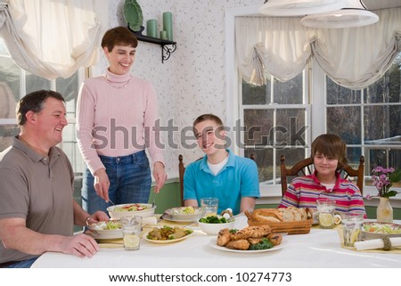 Happy mother and father and their teenage sons eating at the dinner table
