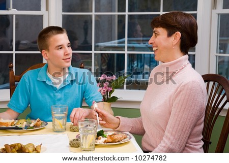 Happy mother and her teenage son eating at the dinner table