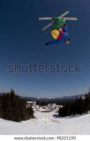 Skier jumping with crossed skis on a dark-blue sky background.