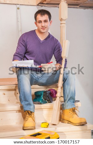 young contractor sitting on wooden ladder in home