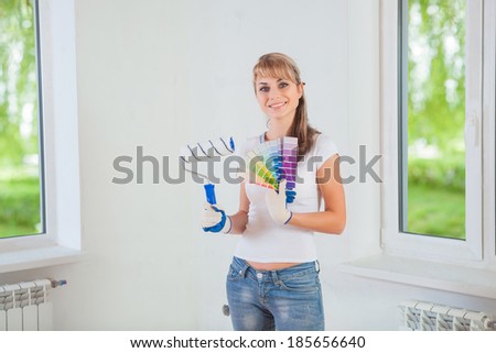 smiling female holding paintroller and color palette at home