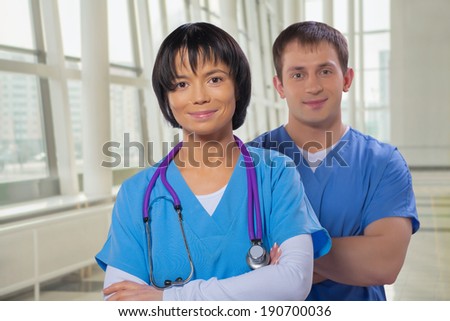 smiling medical team man and woman with crossed arms  looking at camera in modern hospital