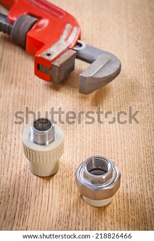 plumbing fixtures and monkey wrench on wooden board