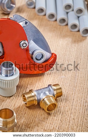 plumbing fixtures and pipe cutter with pipes on wooden board