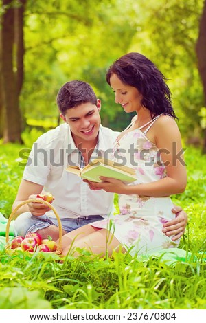 Young beautiful couple sitting on grass in the park smiling and writing book instagram stile
