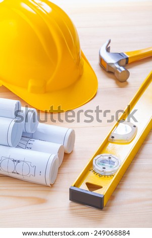 white blueprints construction level yellow helmet claw hammer on wooden board