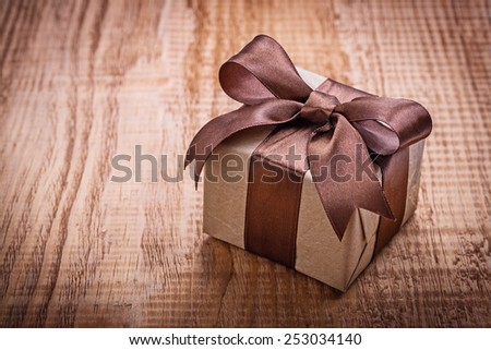single square vintage gift box qith brown bow on old wooden board