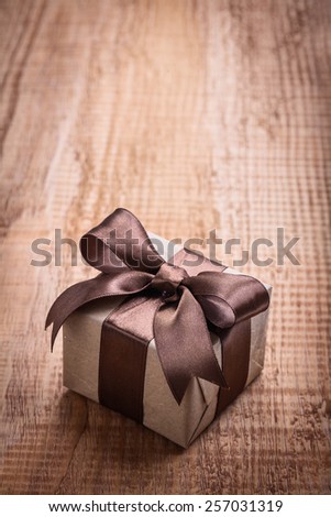 small square vintage gift box with brown bow on old wooden board with copyspace holiday concept