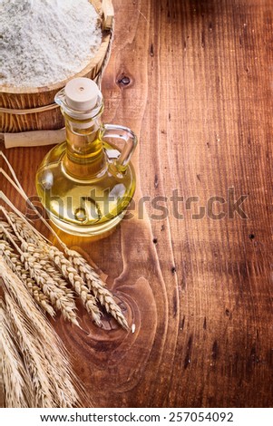 bottle with oil bucket of flour wheat ears on vintage wooden board with copyspace food and drink concept