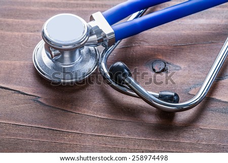 blue medical stethoscope very close up view on vintage wooden board