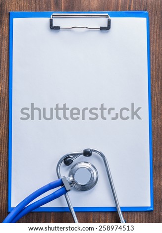 blue clipboard with white blanc sheet of paper on vintage wooden board medical comcept