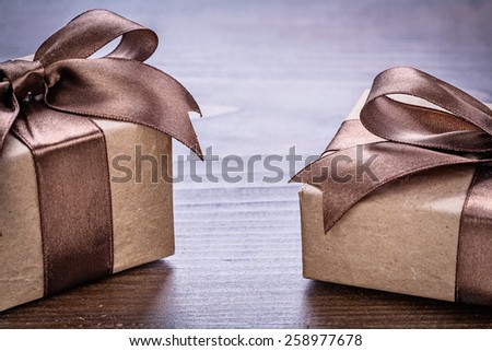 two vintage pepr giftboxes with brown bows on old wooden board very close up view holiday concept