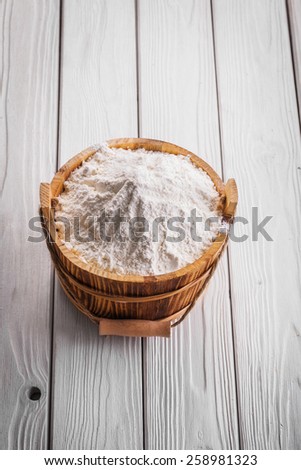 white natural flour in wooden bucket on painted boards food and drink concept