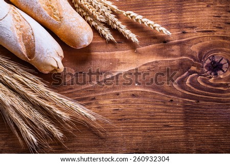 two baguettes ears of wheat and rye on vintage wooden board with organized copyspace food and drink concept