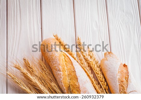 two baguettes and ears of wheat on white painted boards food and drink concept