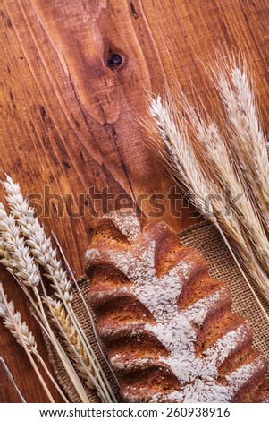 bread and ears of wheat on vintage wooden board food and drink concept